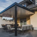 Geschützte Sitzecke durch ein Terrassendach mit geschlossener Wand, für ausreichend Helligkeit sorgt ein Oberlicht in der geschlossenen Wand.