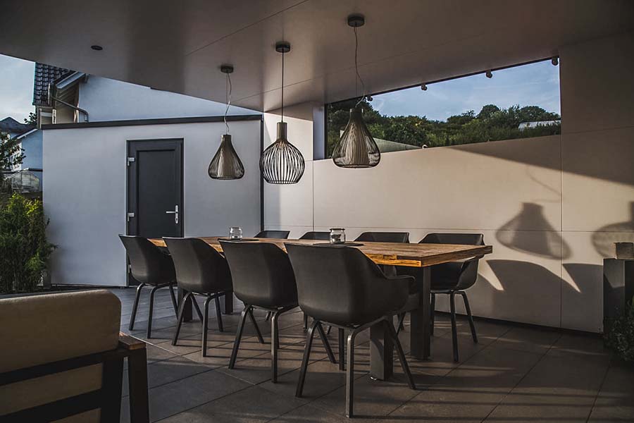 Stylischer Esstisch unter modernem Terrassendach