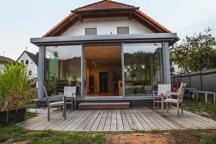 Wintergarten Holz-Aluminium mit geoeffneter Schiebetür zum Garten